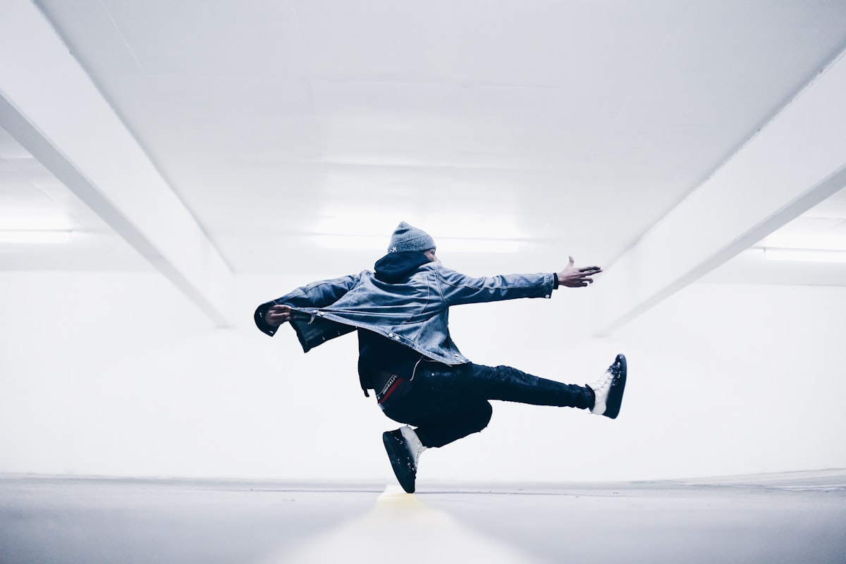 A dancer mid-air in a bright white corridor, seen through the recording camera
