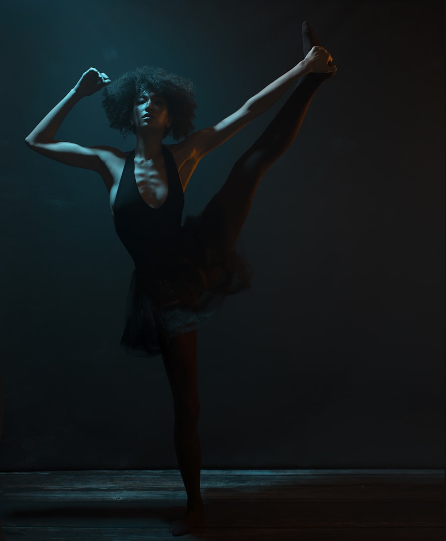 A dancer holding a high kick in low teal light