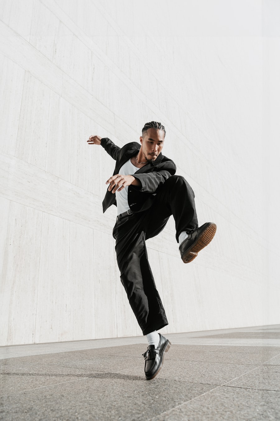 A dancer mid-move in the Choreo Lab practice studio, black outfit against a bright wall